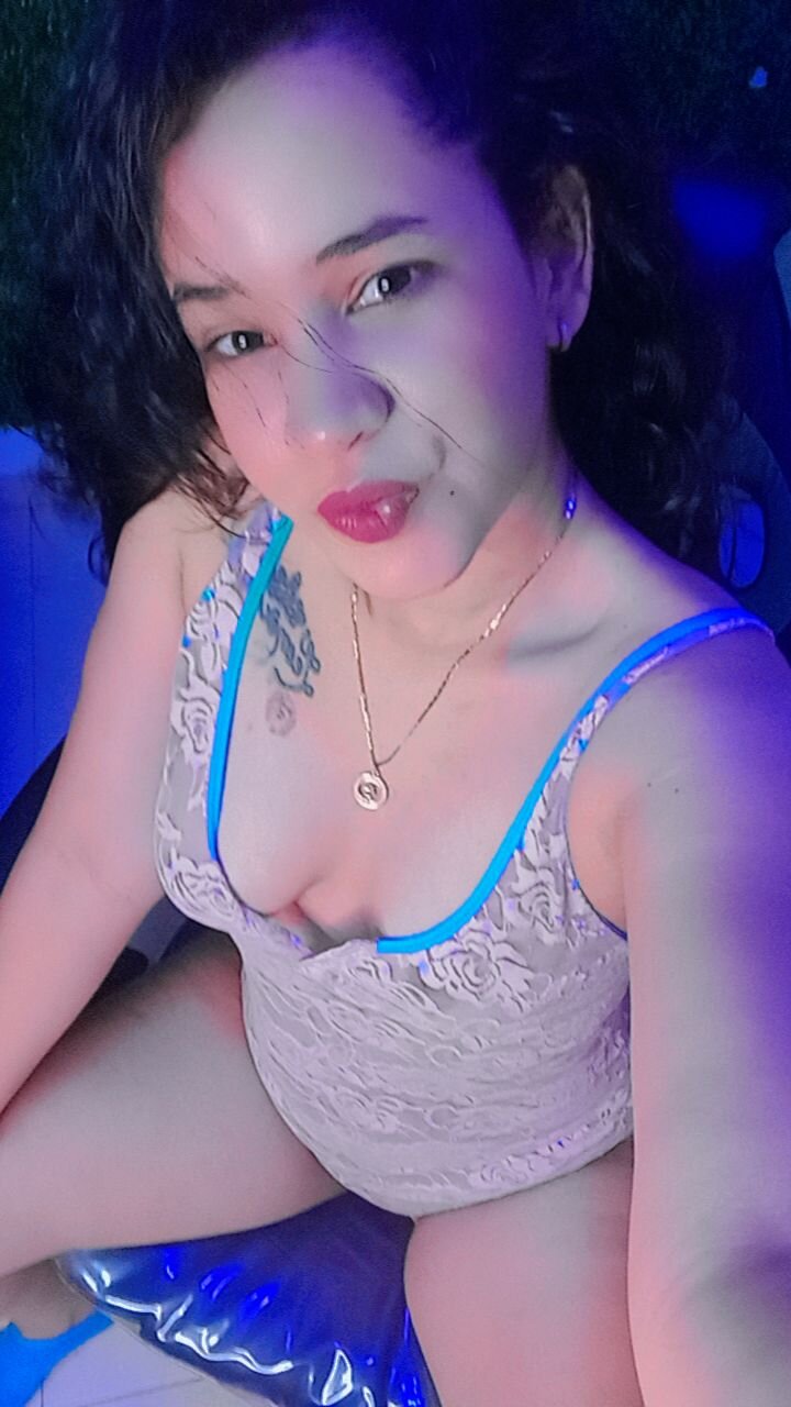 Sarahjonesx smiling suggestively inviting viewers to her live cam